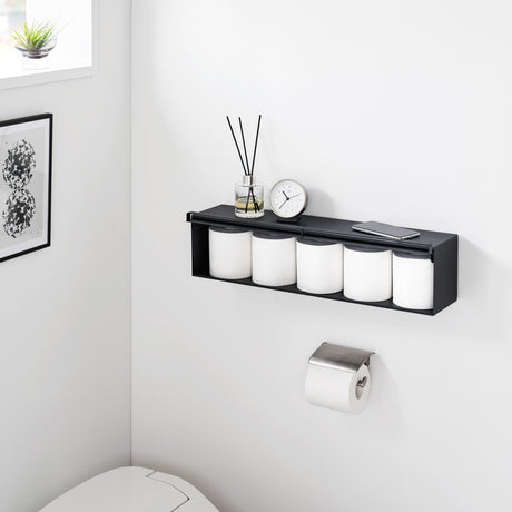 Sort oppbevaringsboks på bad med duftpinner og dekor.