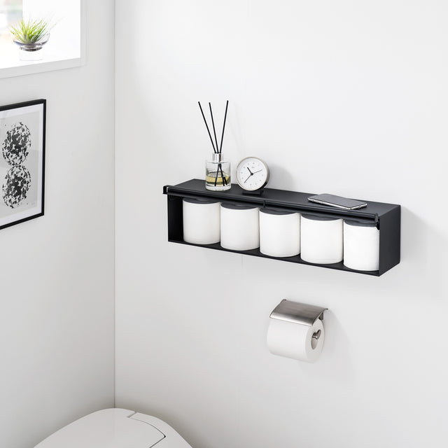 Sort oppbevaringsboks på bad med duftpinner og dekor.