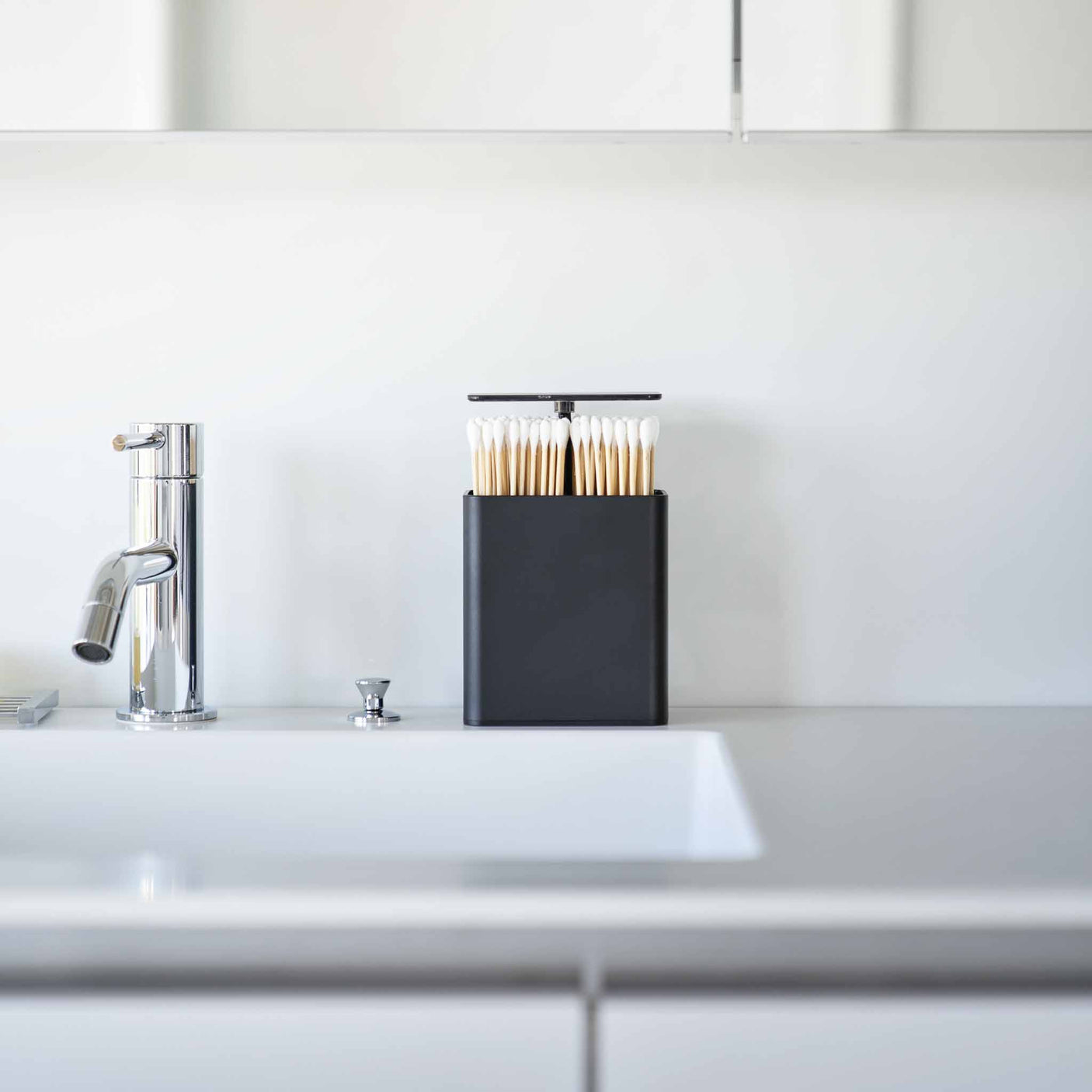 Kompakt sort oppbevaringsbeholder for hårstrikker, pinsetter og bomullspads