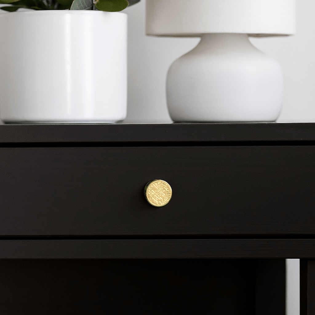 Oslo-knut i guld monterad på en mörk skuff, omgiven av vita dekorativa element som lampa och blomkruka i ett modernt interiör.