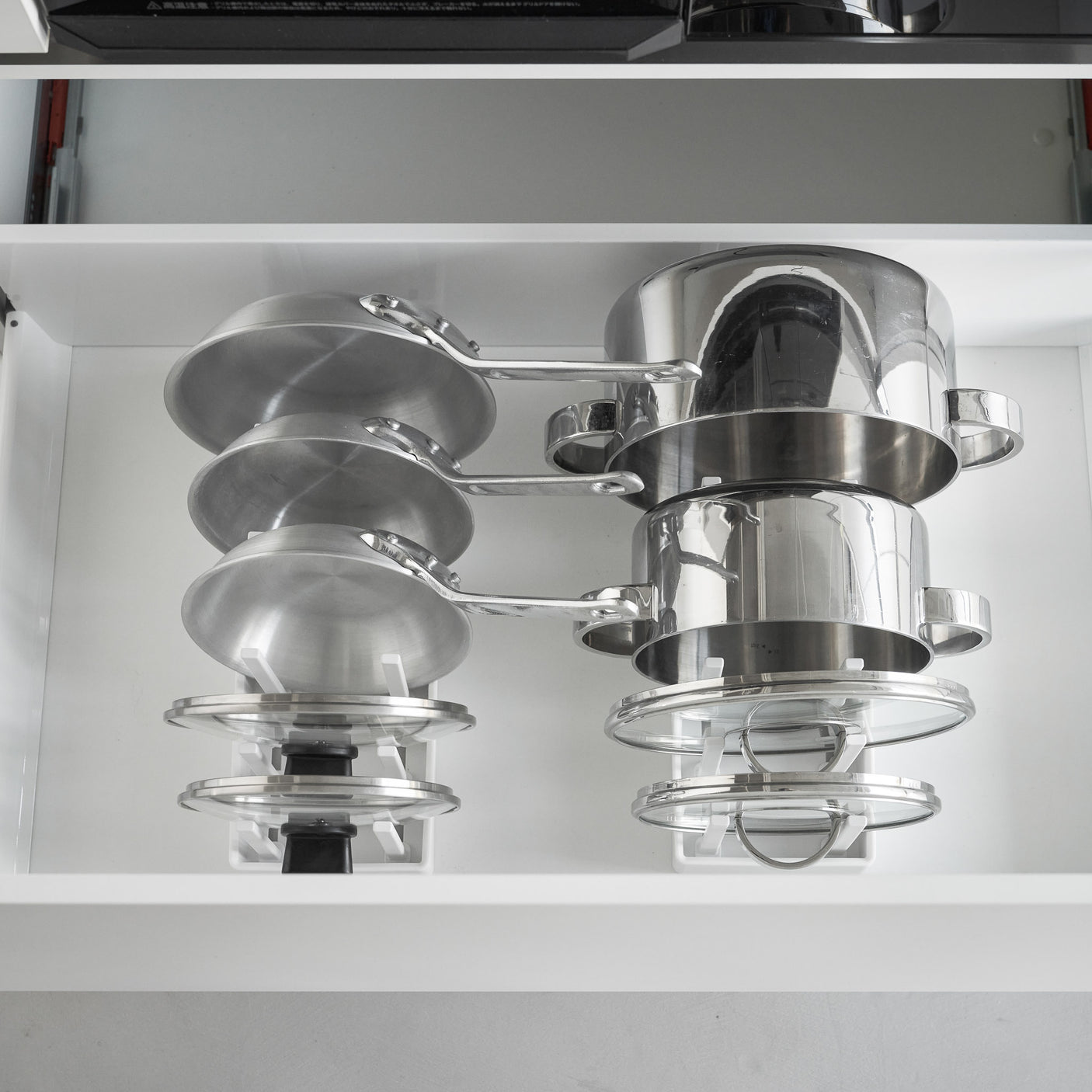 Kjøkkenorganisator med justerbare rom til panner og lokk i hvit farge.