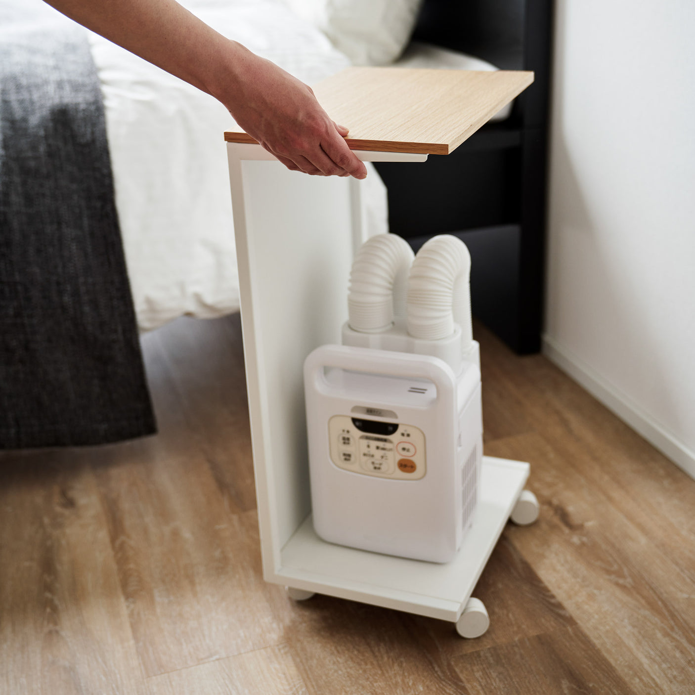 Hvit bord med hjul og lys treplate, perfekt som nattbord eller ved sofaen.