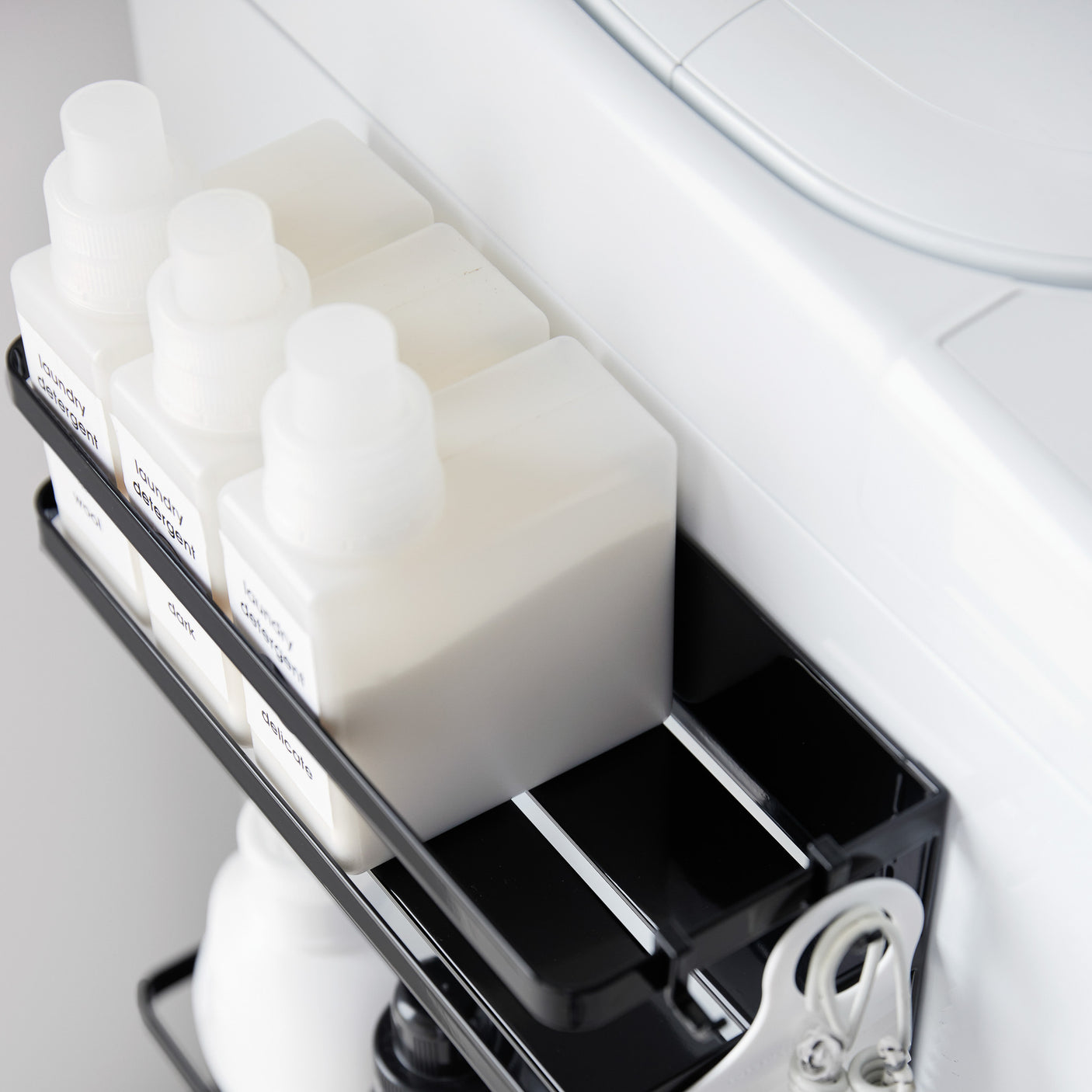 Detaljbilde av magnetisk oppbevaringshylle i sort metall med to nivåer.