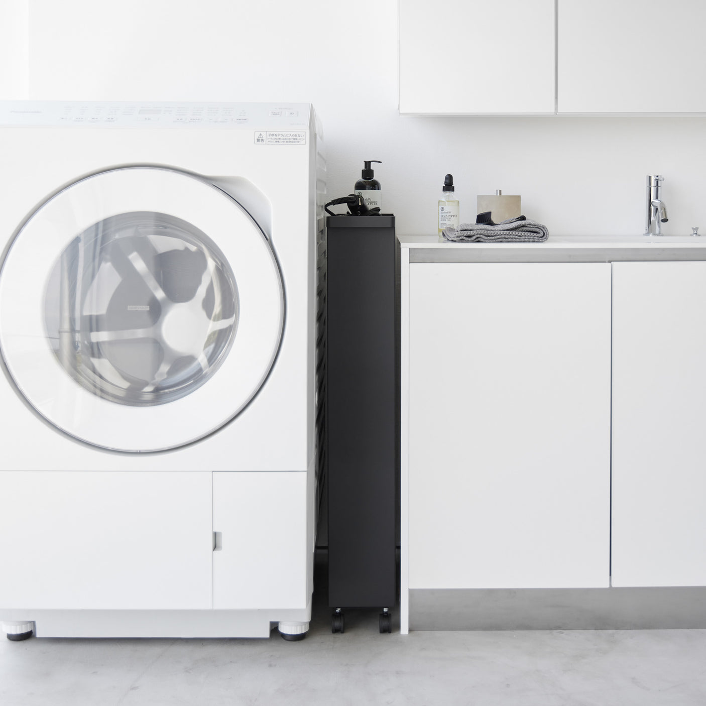 Detaljbilde av sorte hjul på oppbevaringsvogn med fire hyller.