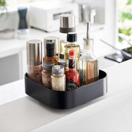 Roterende oppbevaringsbrett i sort for organisering av kjøkkenartikler.