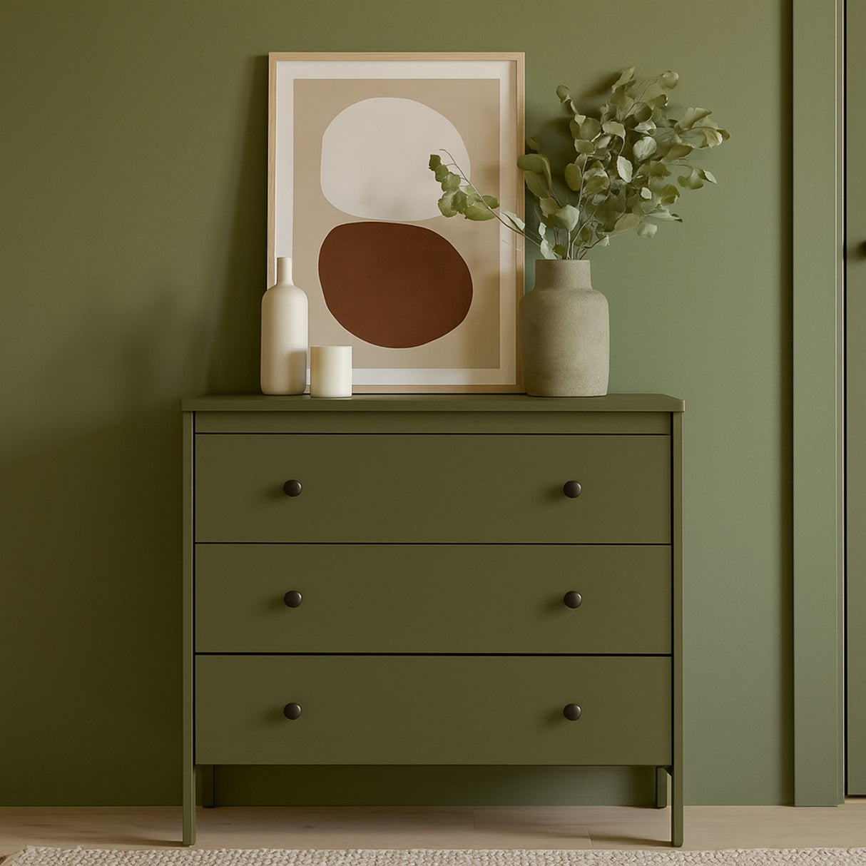 kommode med olivengrønn kontaktplast mot grønn vegg, pyntet med kunstverk, vaser og planter på toppen.