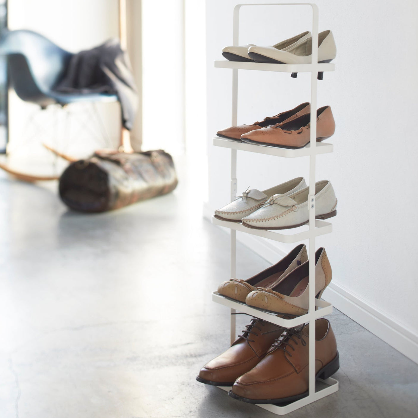 Hvit skohylle med fem nivåer, plassert i en lys entré med sko ryddig organisert.