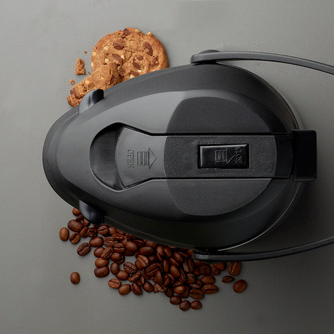 Pumplåset fra oven med OPEN- og CLOSE-markering, kaffebønner ved siden af