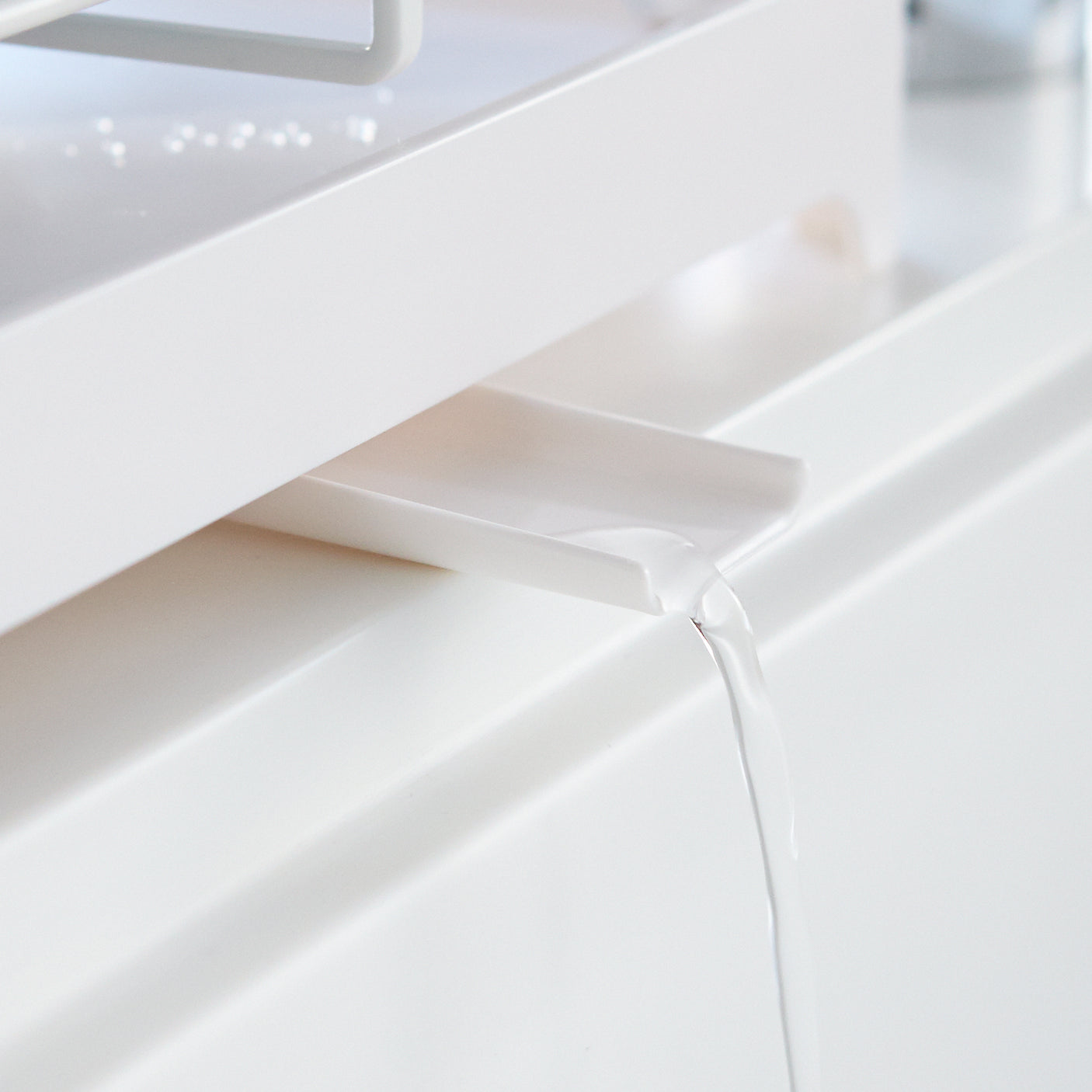 Stilrent hvitt oppvaskstativ i metall med en smart drypprenne for effektiv avrenning.