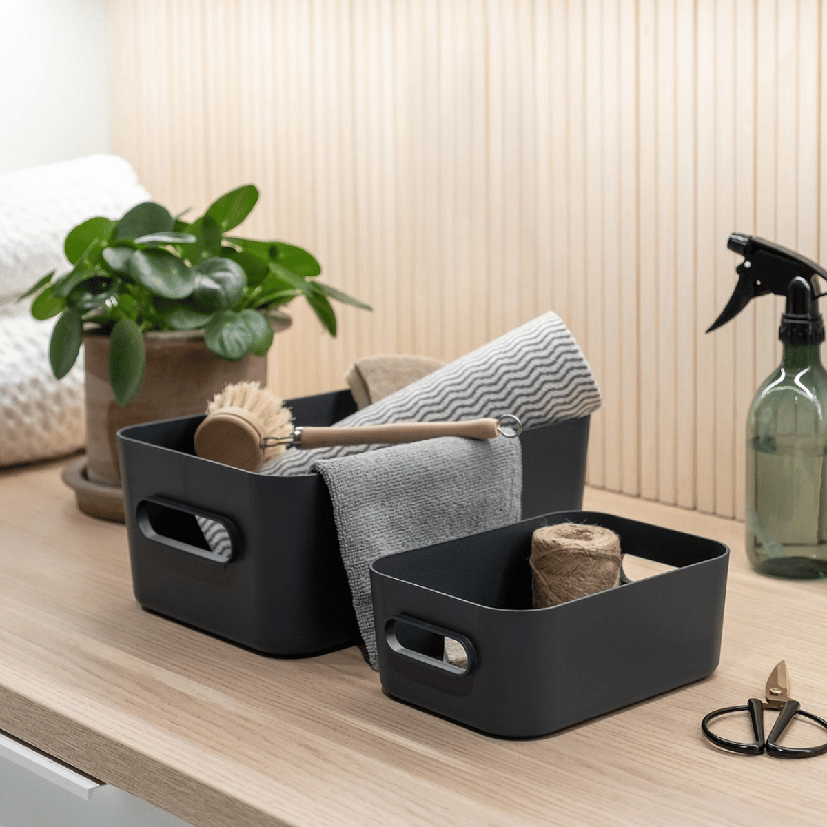 To koksgrå SmartStore Comfort oppbevaringskurver med oppvaskbørste, klut og rengjøringsutstyr på benk