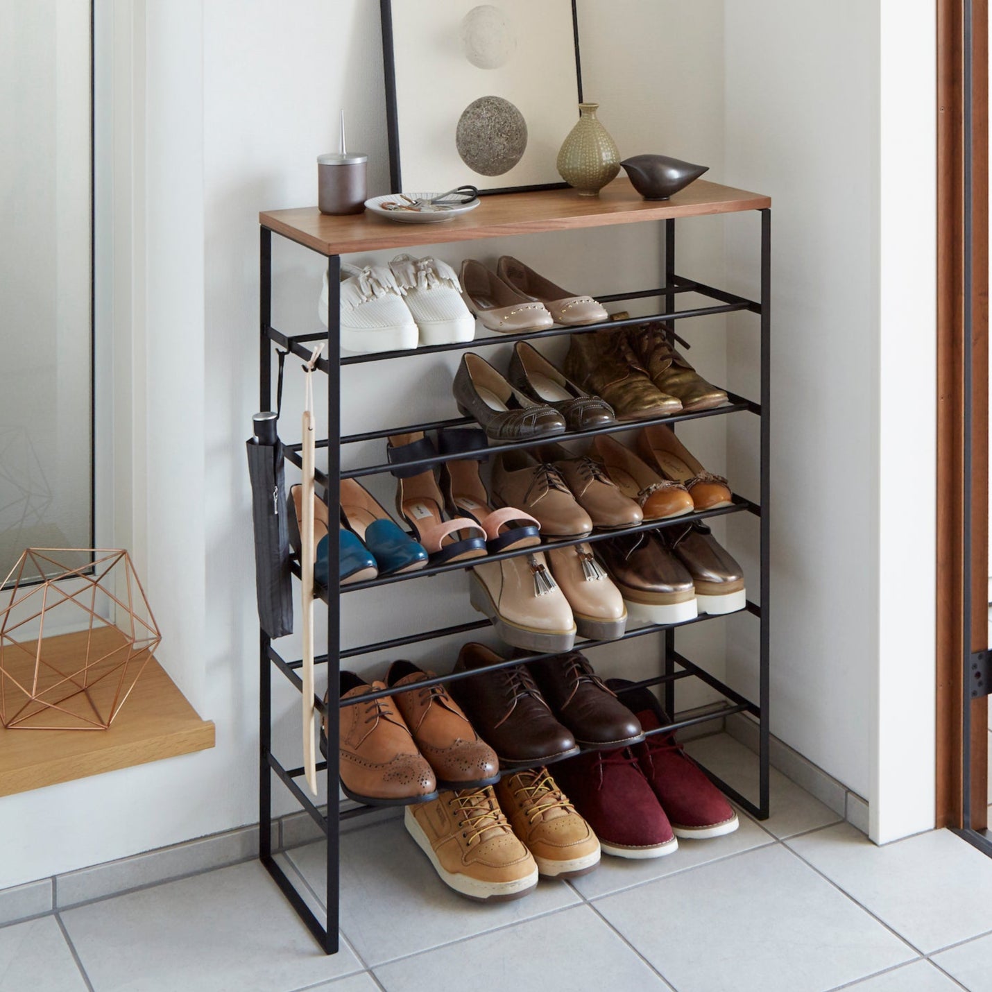 Sort skostativ med seks hyller og treplate på toppen.