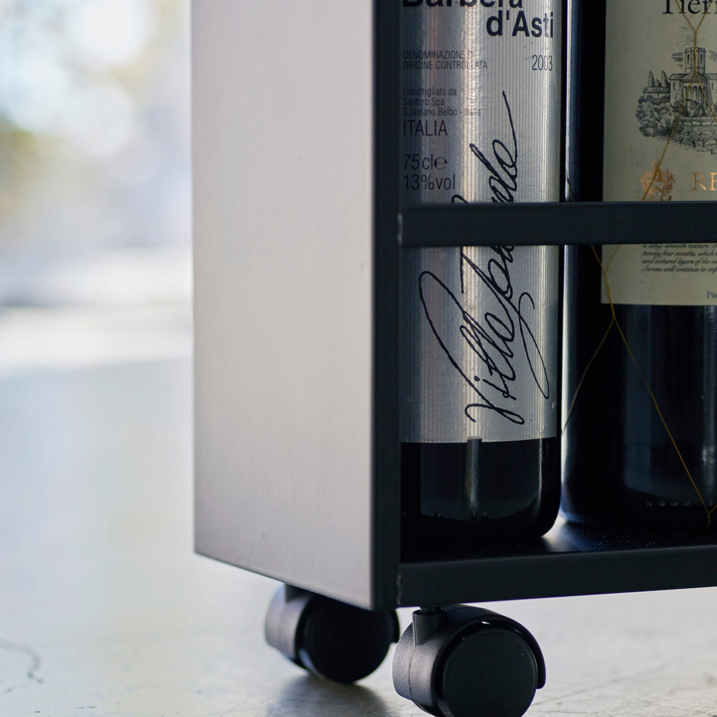 Stilig sort oppbevaringsvogn med trehylle på toppen.