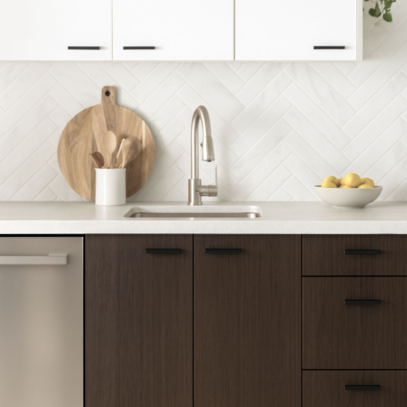 Moderne kjøkken med Cocoa kontaktplast på skap, hvit benkeplate, fiskebensfliser og dekor i tre og friske sitroner.