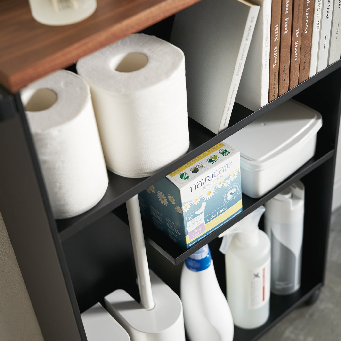 Hylle med plass til rengjøringsmidler, papir og bøker.