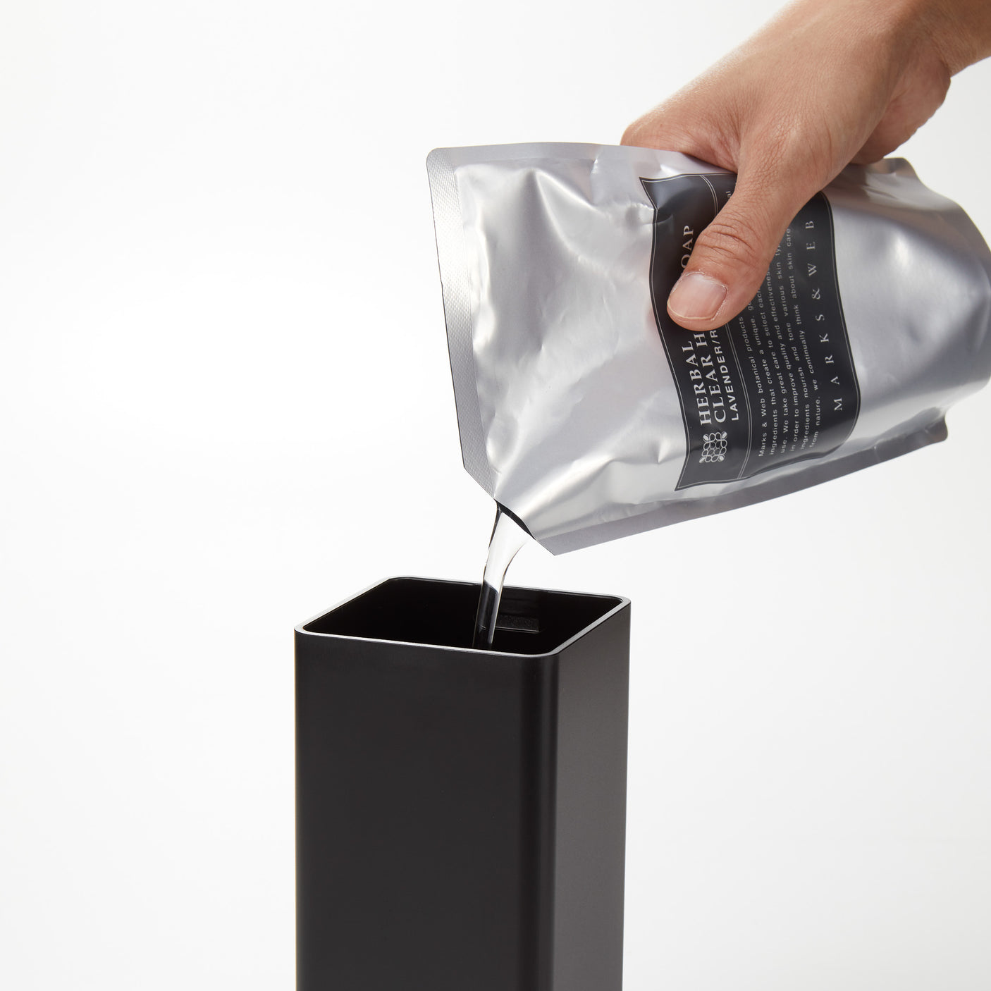 Detaljbilde av sort magnetisk oppvaskflaske med lokk.