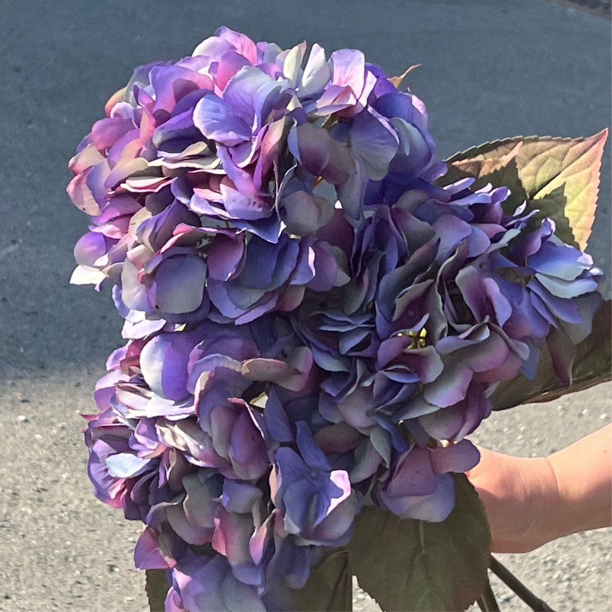 Kunstig hortensia i vase på bord med dekorativt blomsterhode