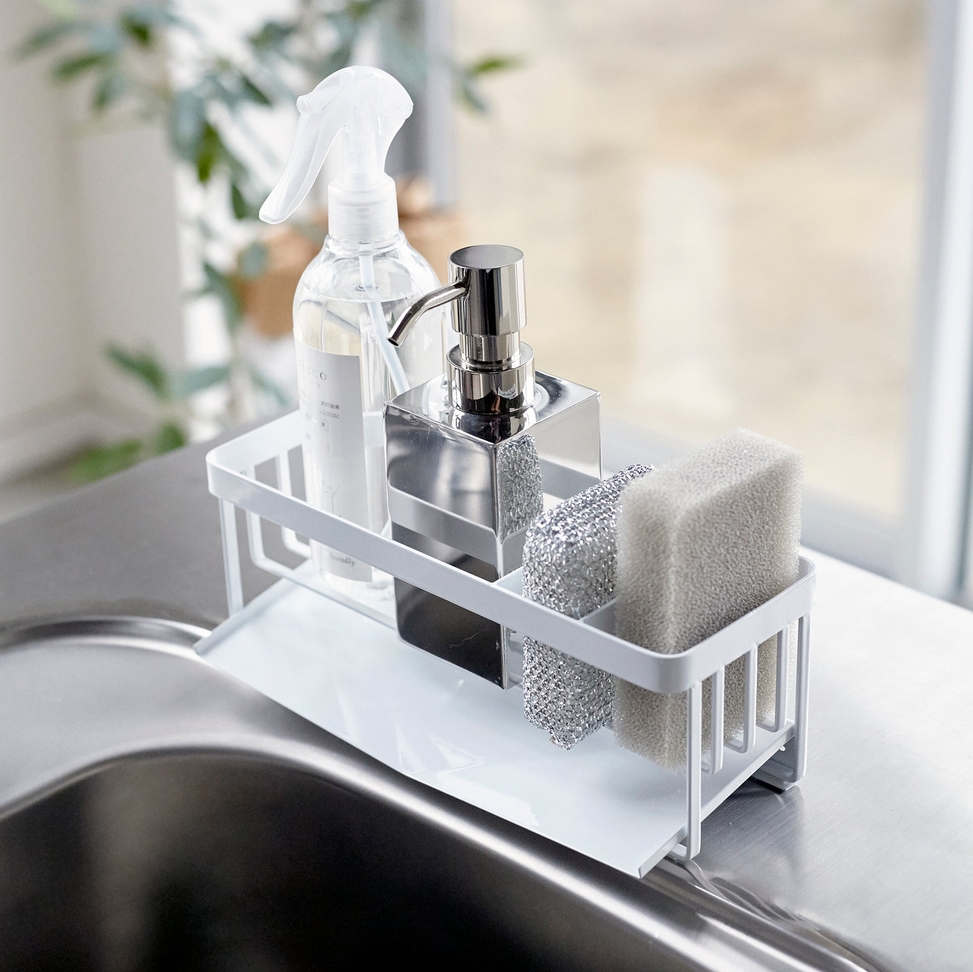 Hvit såpeholder på kjøkkenbenk med såpedispenser, svamp og børste.