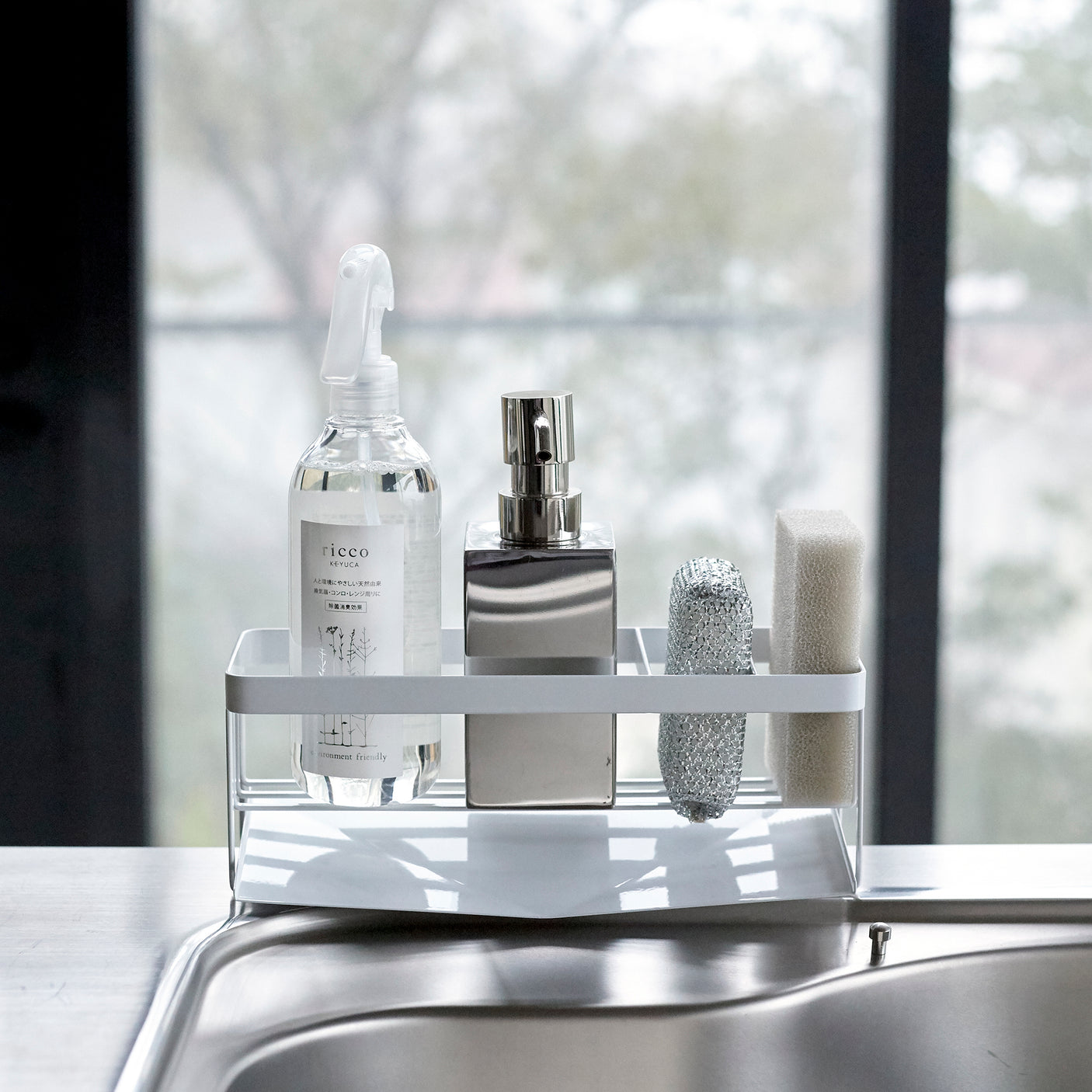 Moderne hvit såpeholder med rengjøringsartikler på kjøkkenbenk.