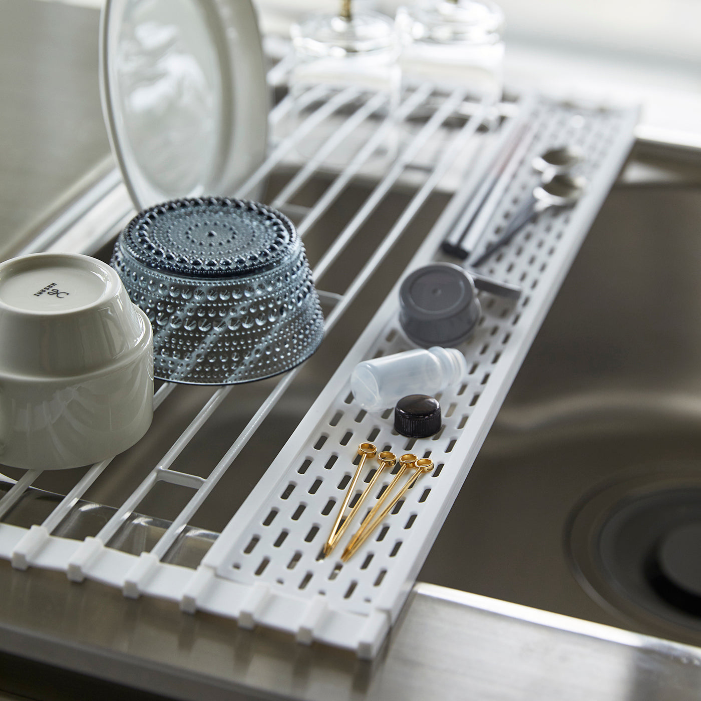 Hvit kjøkkenrist for tørking av servise over vask.