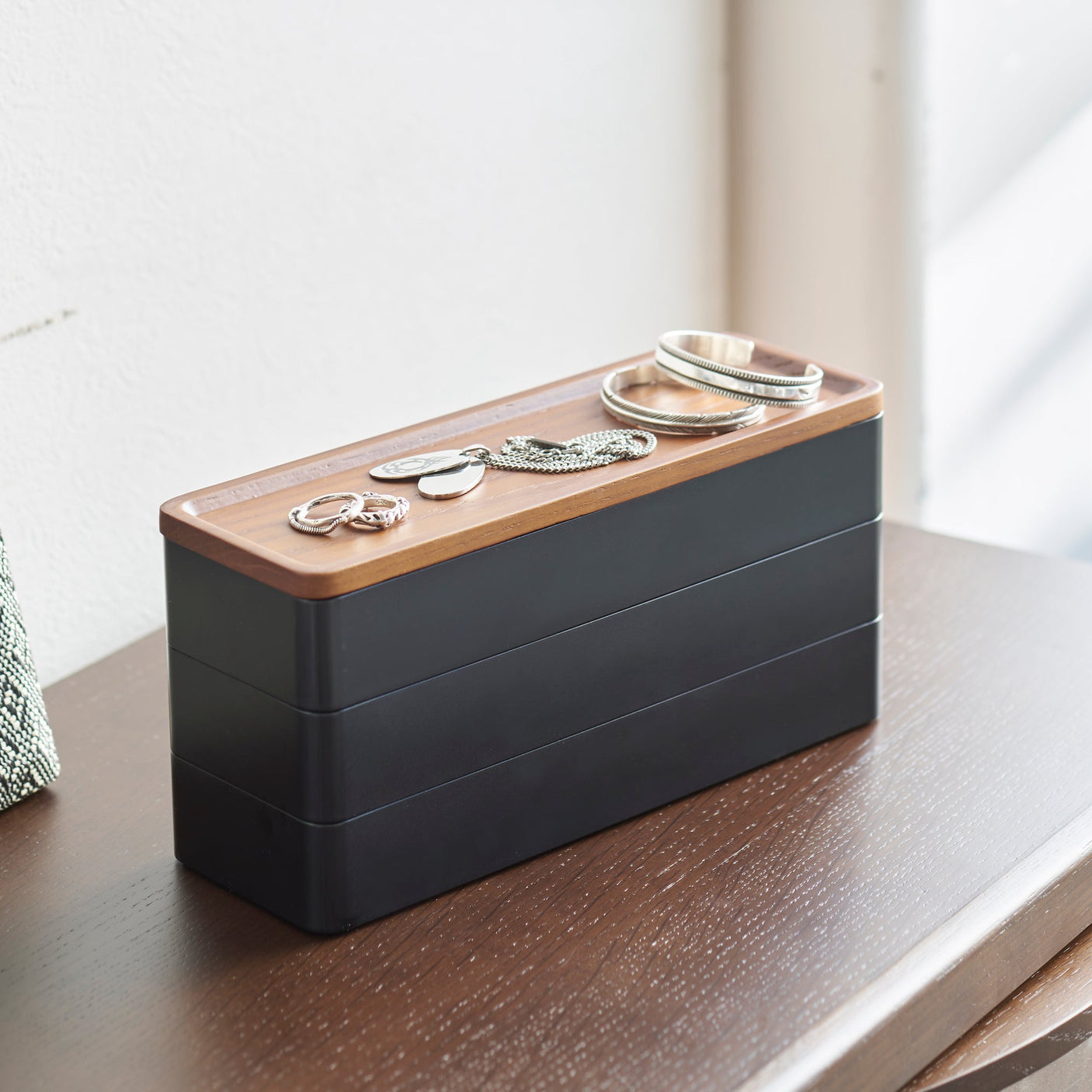 Sort oppbevaringsboks med trelokk for smykker og småting.