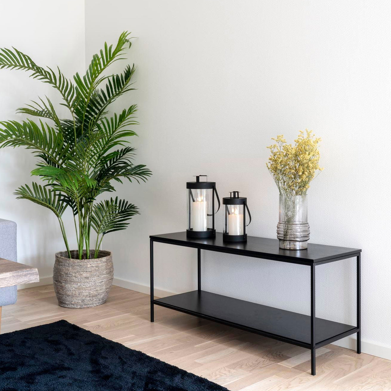 Sort glasslanterne plassert på benk i stue