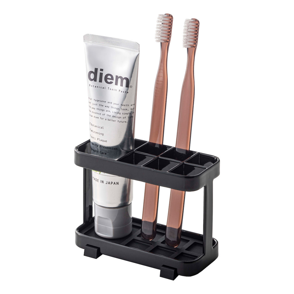 Sort tannbørstestativ med plass til tannkrem og børster.