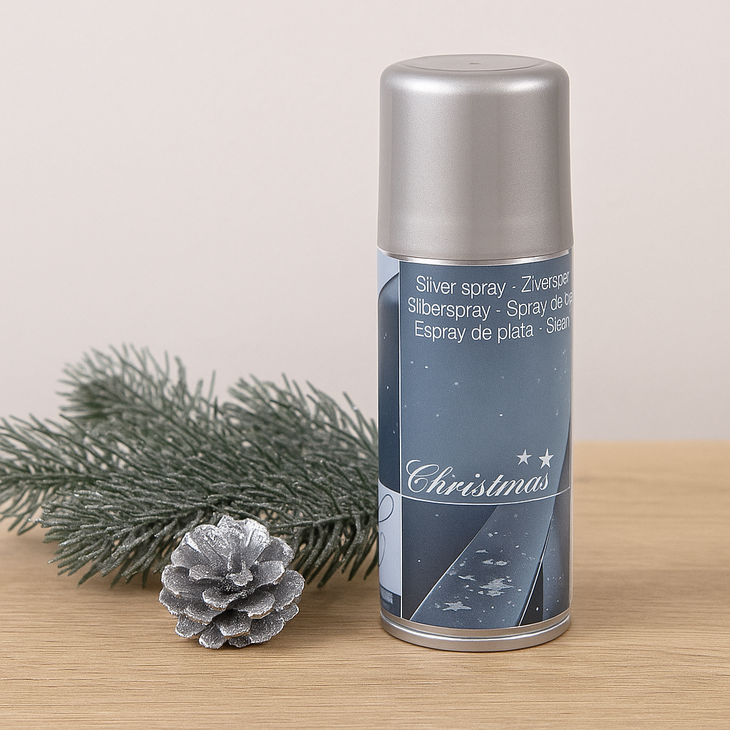 Sølvspray 150 ml plassert på bord med granbar og en sølvfarget kongle ved siden av, gir et enkelt og festlig uttrykk.