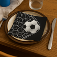 Serviett med fotballmotiv ligger på tallerken på et sporty dekket bord.