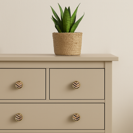 Knotter i børstet messing med marketeri mønster montert på beige kommode. Stilfull detalj som gir et eksklusivt og personlig preg til oppbevaringsmøbler i hjemmet.