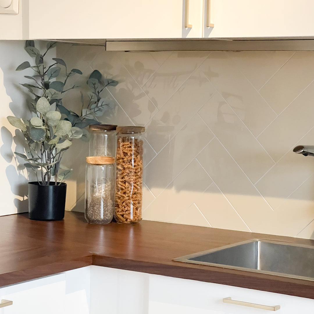 Hailey beige fliser i fiskebensmønster montert på kjøkkenvegg – gir lun og eksklusiv stil.