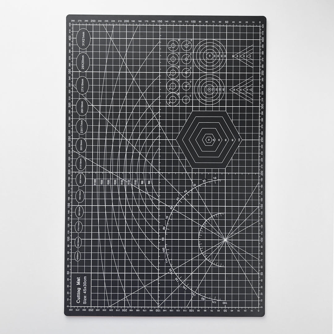 Svart skjærematte med hvite linjer og mønster for presise kutt, ideell for hobby og håndverk.