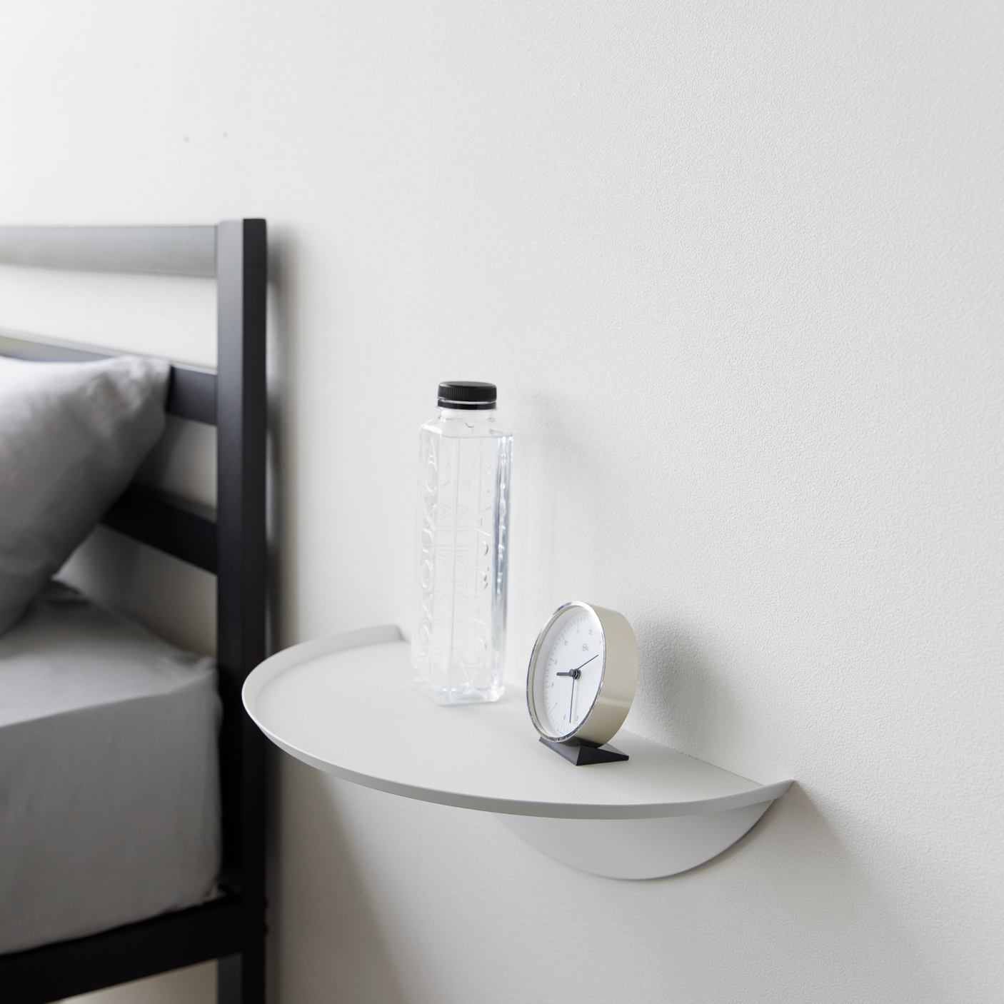 Halvrund vegghylle i sort metall for praktisk oppbevaring.