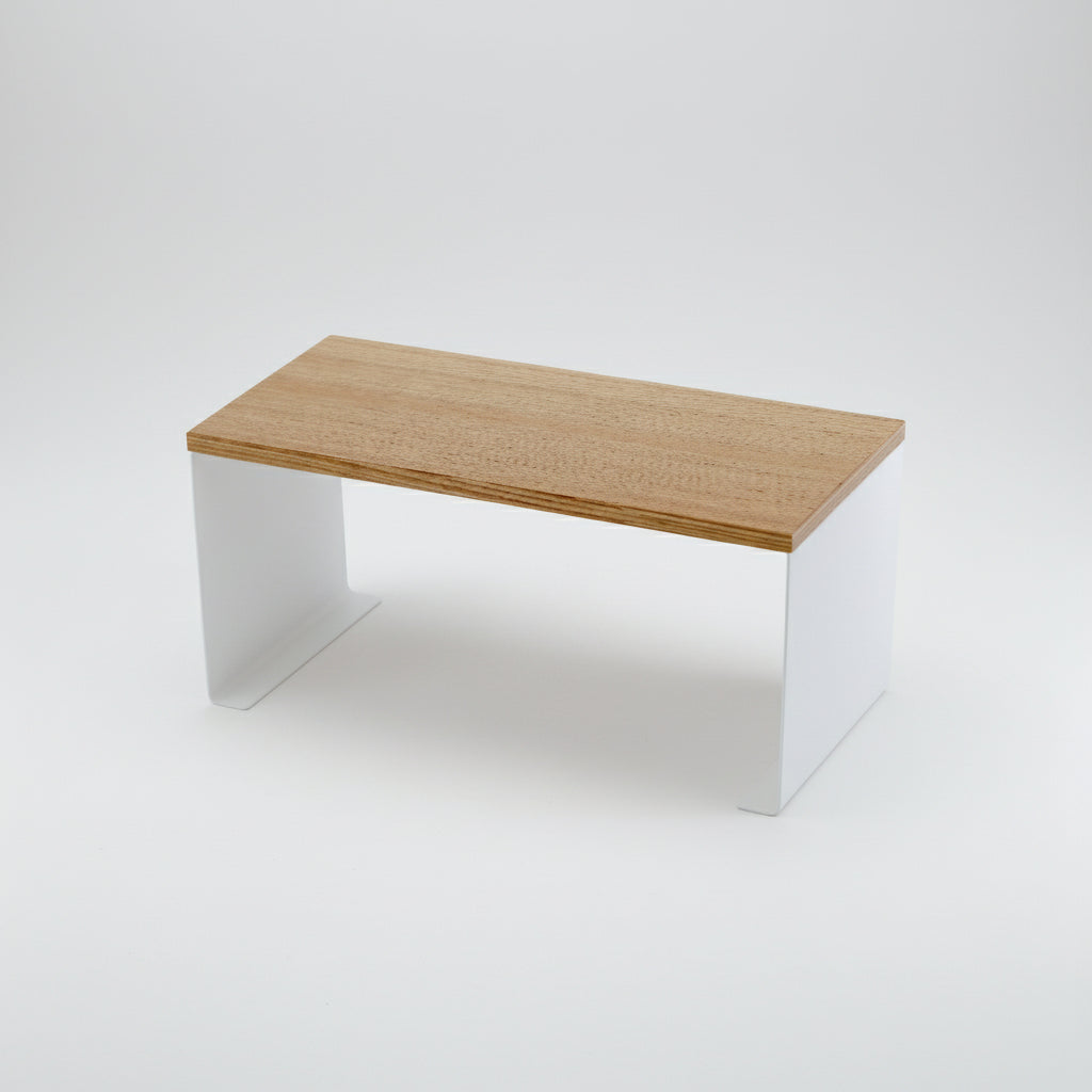 Stabelbar hvit kjøkkenhylle med treplate på benkeplate med kopper og skåler.