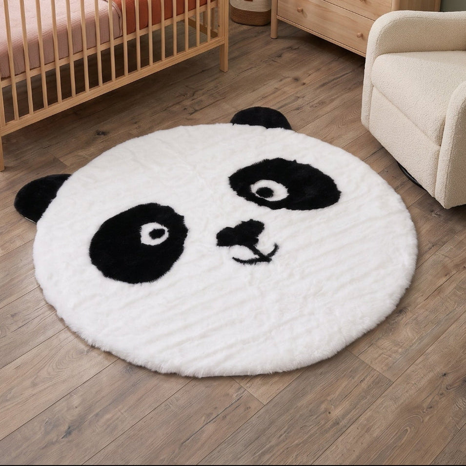 Rundt pandateppe i svart og hvitt på tregulv, mykt barneteppe med pandaansikt og 100 cm diameter til barnerom.