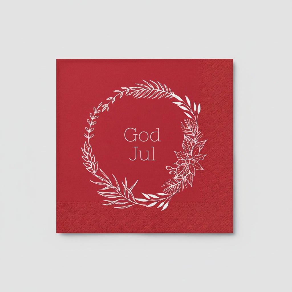 Julestemning med serviett med hvit krans og «God Jul»-tekst på dekket bord.