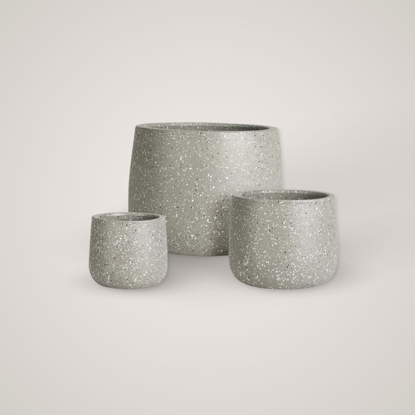 Tre tomme terrazzo-krukker i ulike størrelser plassert mot en lys beige bakgrunn.