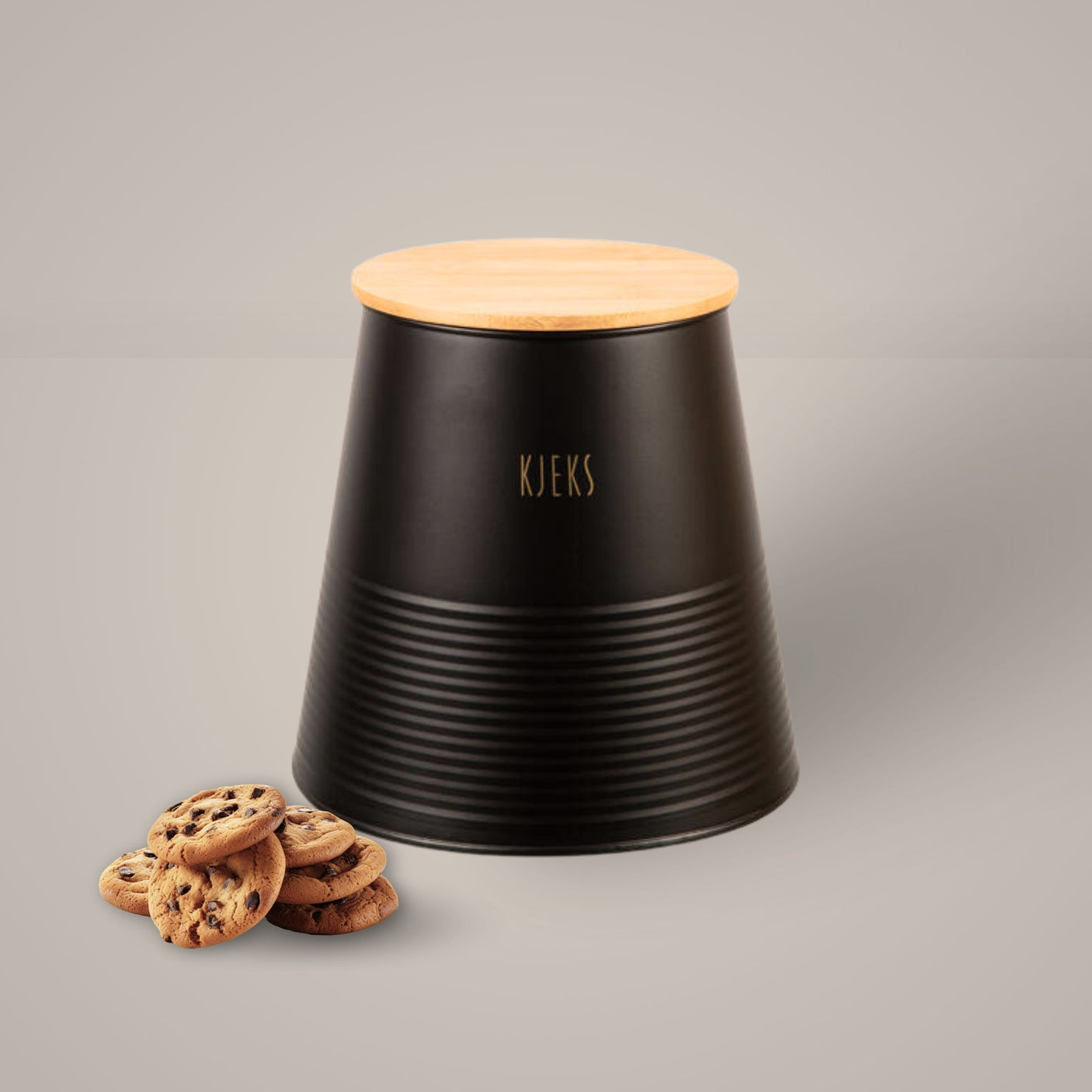 Sort metallboks med bambuslokk og gulltekst «Kjeks», plassert på kjøkkenbenk med kjeks ved siden av.