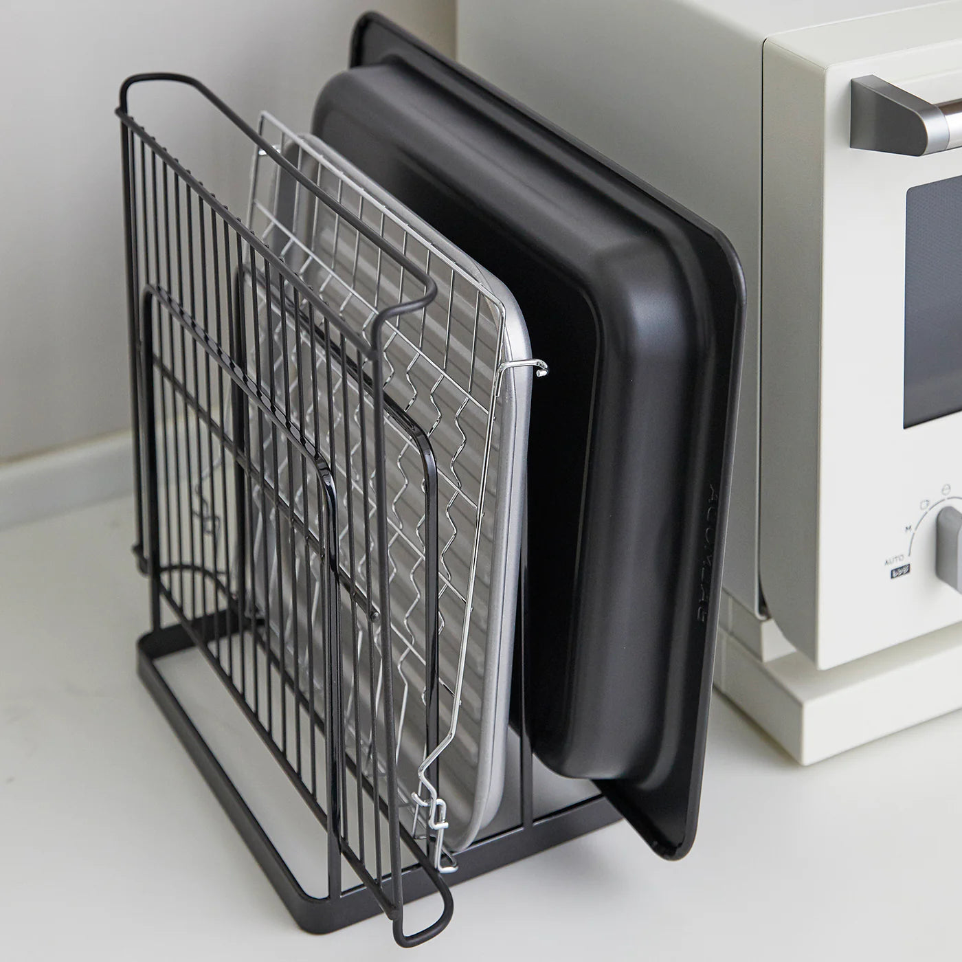 Svart holder med tre rom for brett og kjøkkenutstyr