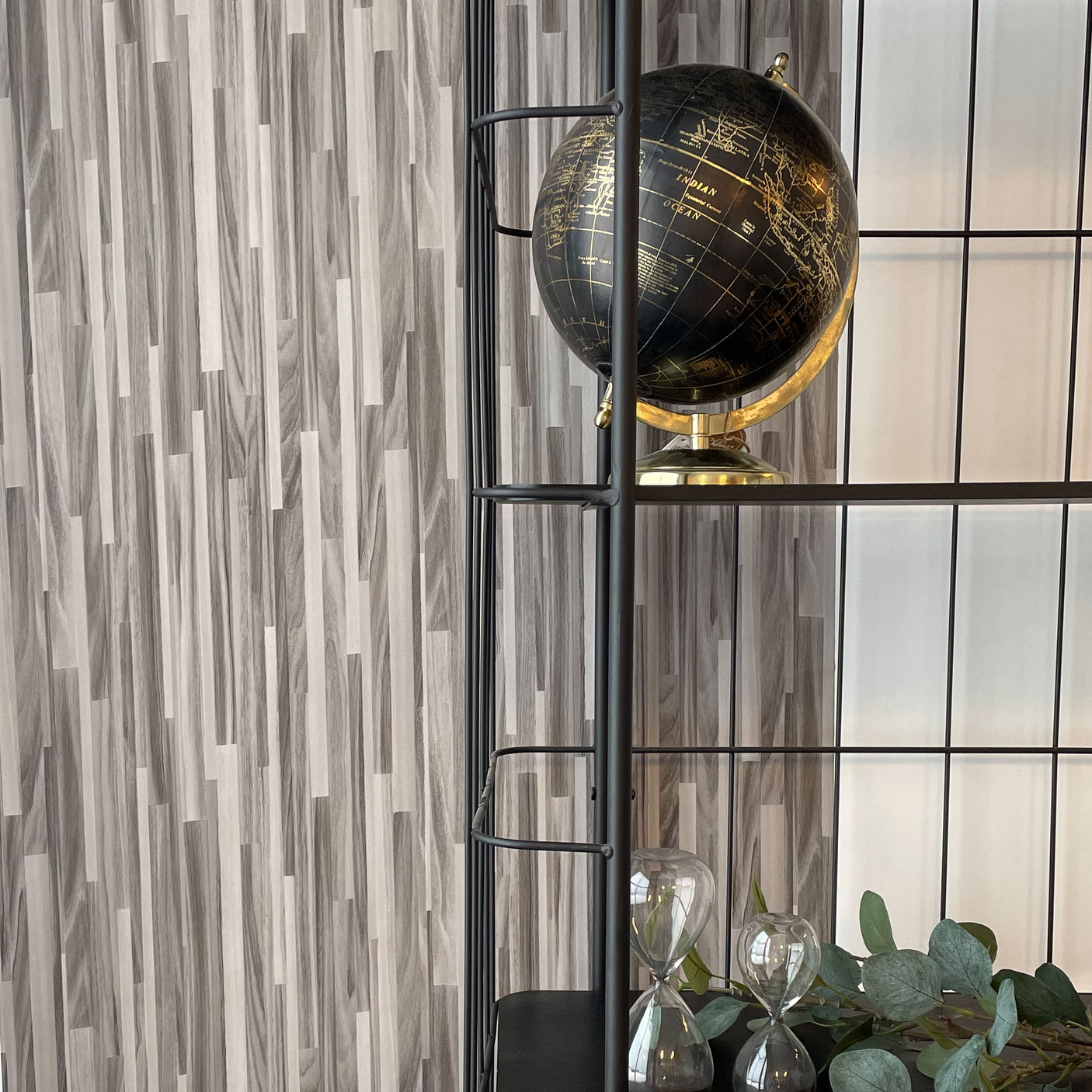 Stilren hylle med globus foran kontaktplast i naturtro treverkdesign.