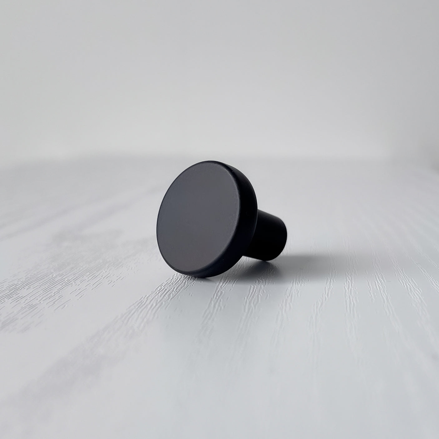 Sort moderne knott i matt metall sett fra siden, med skrue synlig i bakgrunnen.
