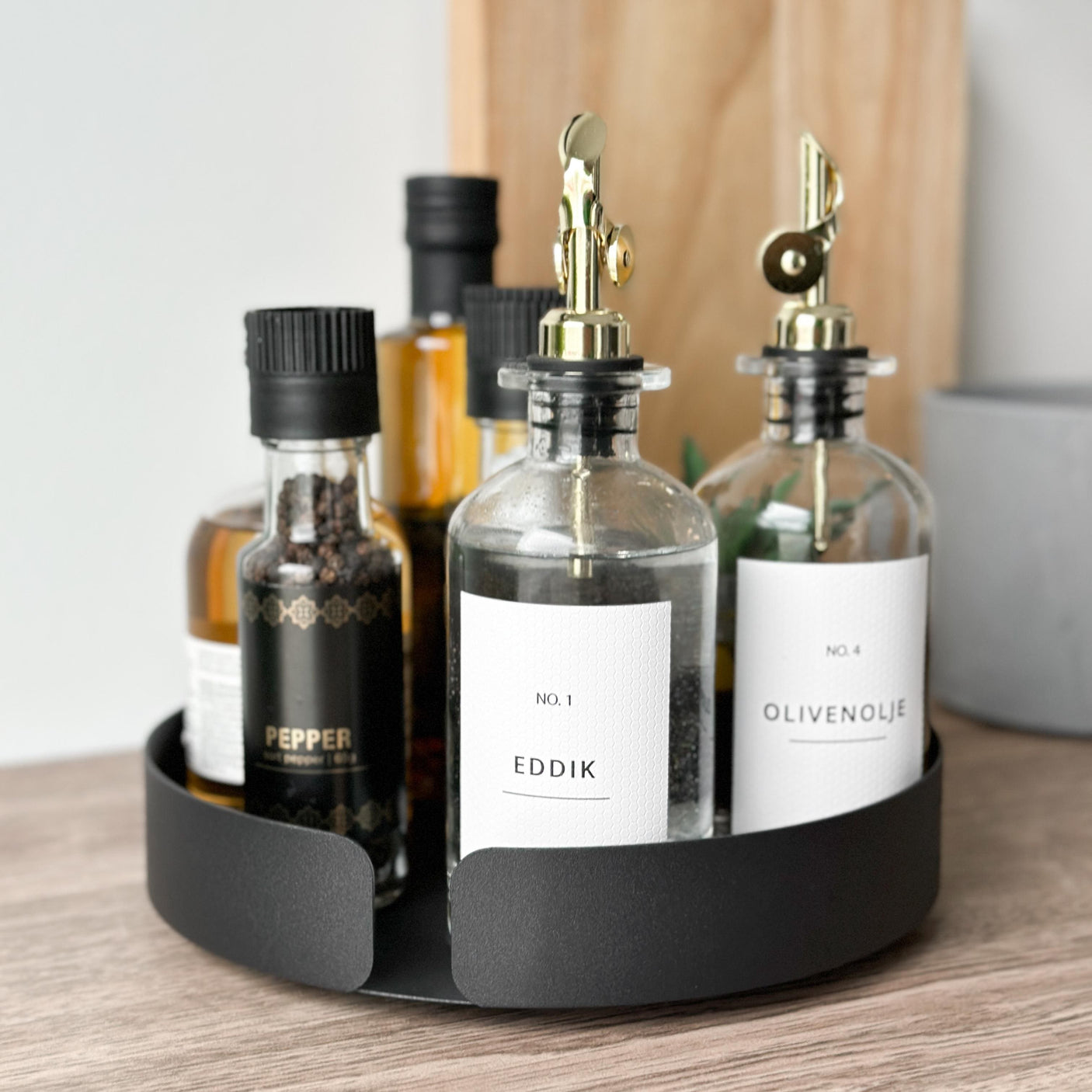 Sort snurrebrett med glassflasker for eddik og olivenolje – ideelt for praktisk og estetisk organisering av daglige kjøkkenfavoritter.