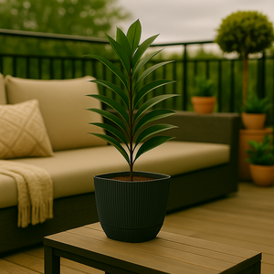 Plante i mørkegrå, rillet plastpotte plassert på bord i stilfull veranda med utemøbler og grønne omgivelser.