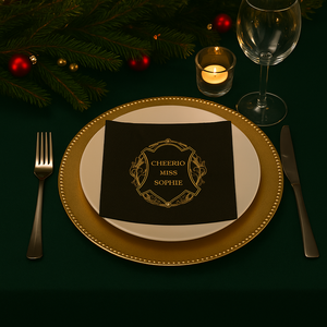 Juledekket bord med gullkantet tallerken og sort serviett med teksten "Cheerio Miss Sophie" i gull.