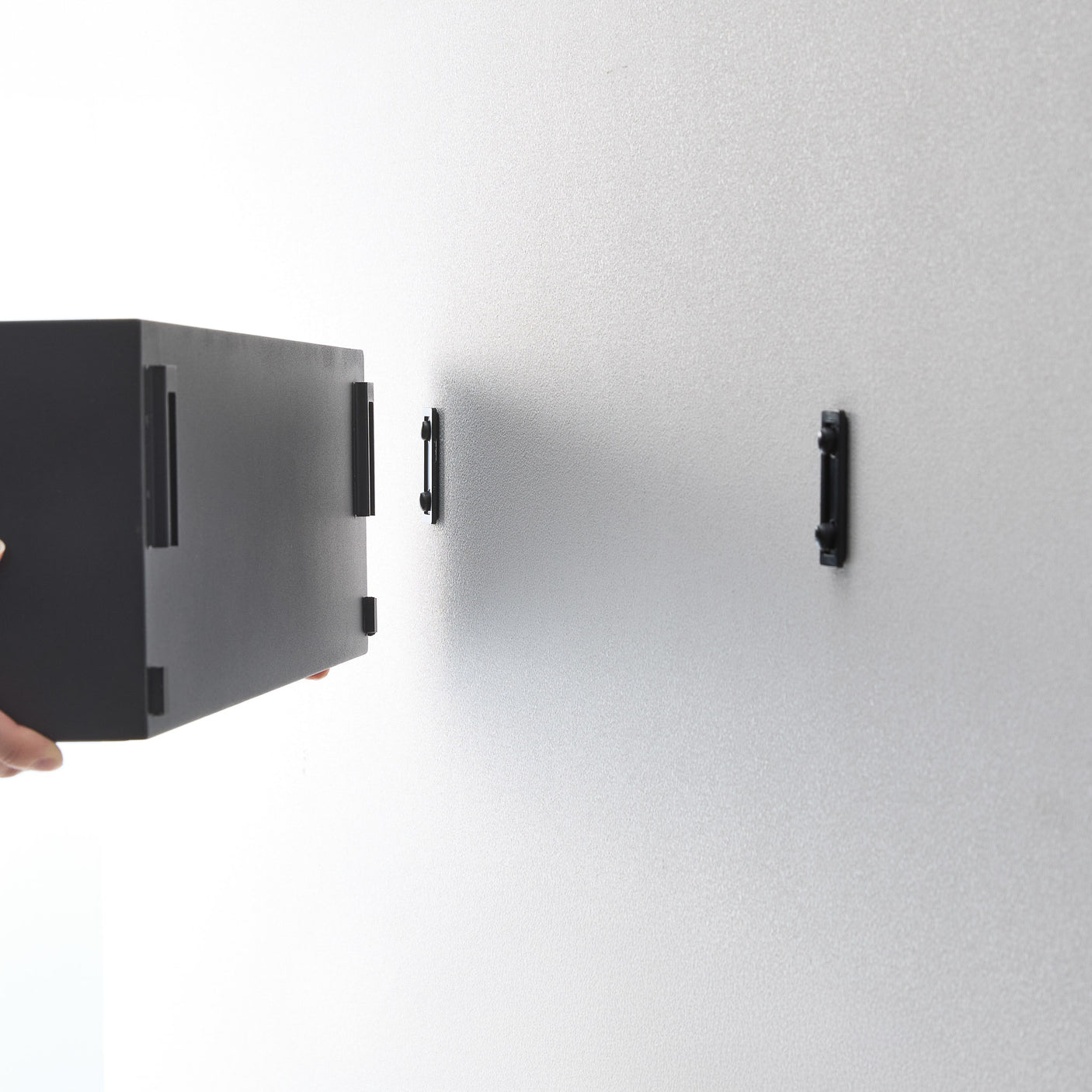 Moderne sort metallboks festet på hvit vegg i gang.