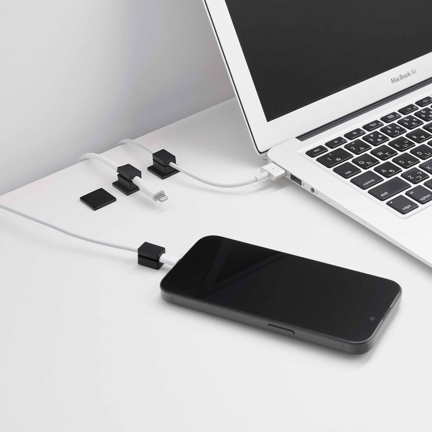 Sort kabelholder i silikon med selvklebende base til ladekabler