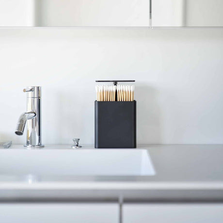 Kompakt sort oppbevaringsbeholder for hårstrikker, pinsetter og bomullspads