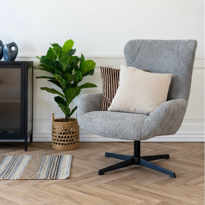 Besica Lounge stol i mørk grå plassert i stue med bord og dekor