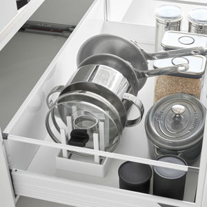 Hvit oppbevaringsholder for gryter, lokk og stekepanner i skuff.