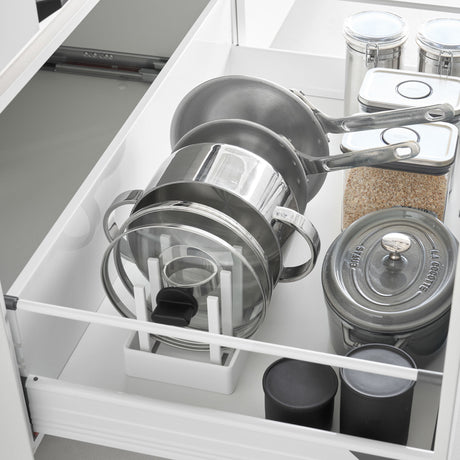 Hvit oppbevaringsholder for gryter, lokk og stekepanner i skuff.
