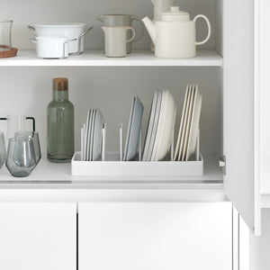 Justerbar gryteholder i hvit plast brukt i kjøkkenskuff med gryter og lokk.